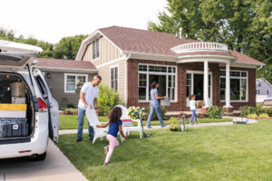 Young family in front yard of brick home with gorgeous windows and doors