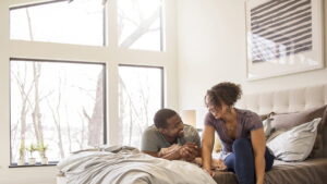 Man and woman laughing in front of big picture windows