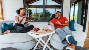 Man and woman sitting outside enjoying a charcuterie board with a sliding window in the background